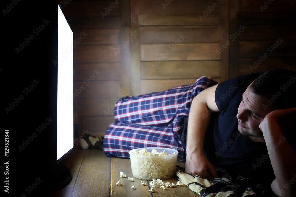 Fototapeta premium young man watching television at home on the floor