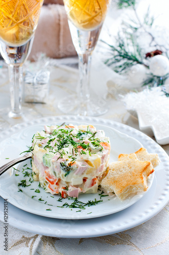 Traditional Russian Christmas Salad "Olivier" on a white plate in the Christmas decor