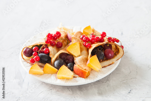 pancakes with berries in a plate on a table, selective focus