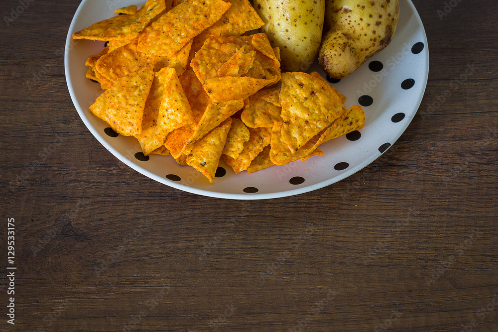 Corn chips with potatoes on the table with nature light in low key tone. Corn chips with potatoes on the table with nature light in low key tone.