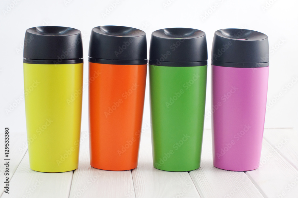 Color thermos mugs on the white wooden table Color thermos mugs on the white wooden table