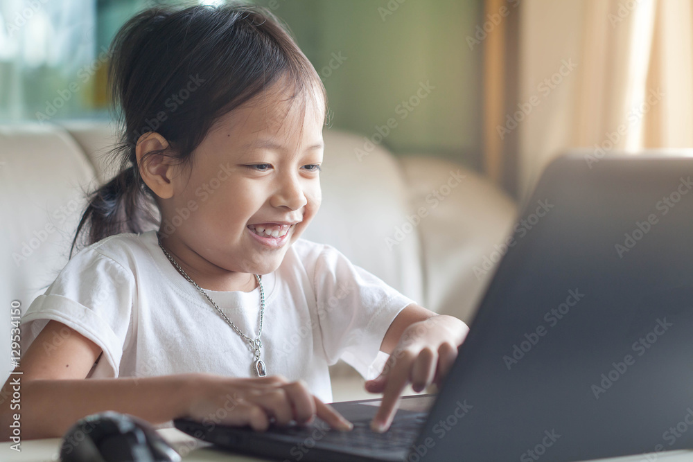 Cute little child smiling and looking at laptop in room at home. Cute little child smiling and looking at laptop in room at home.
