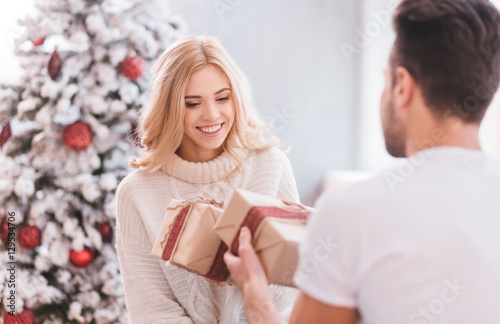 Positive delighted couple giving each other Christmas gifts