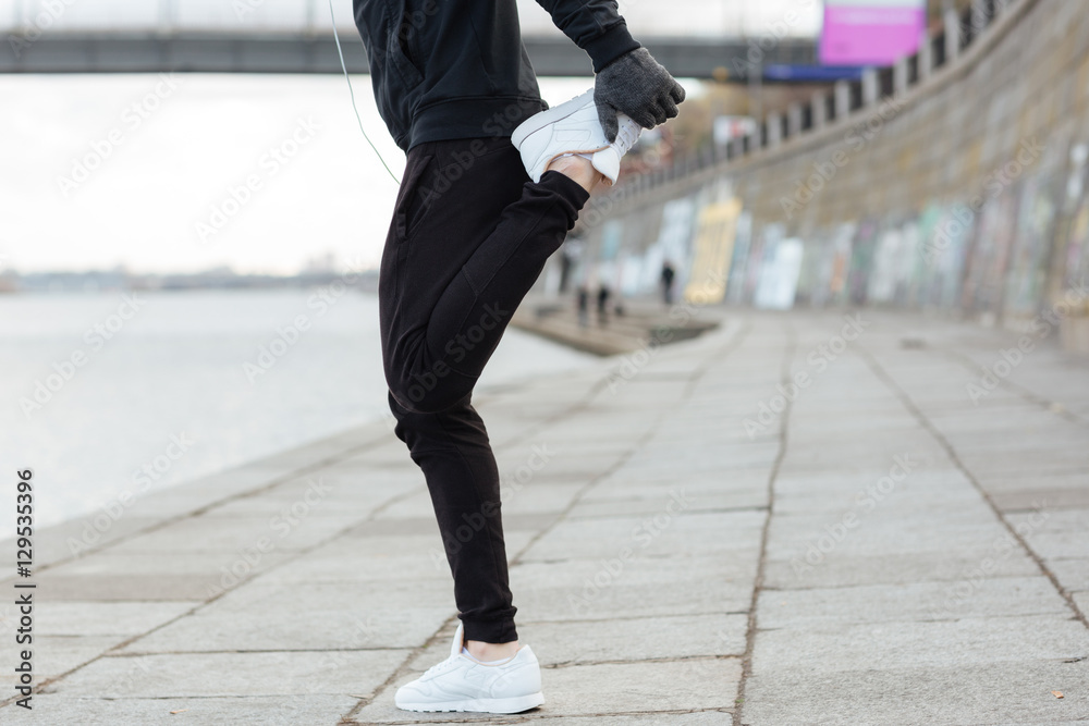 Man athlete standing and stretching legs outdoors Man athlete standing and stretching legs outdoors