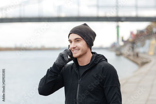 Man in hat and gloves talking on mobile phone outdoors