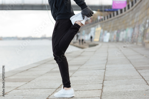 Man athlete standing and stretching legs outdoors