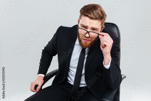 Serious business man in glasses on armchair