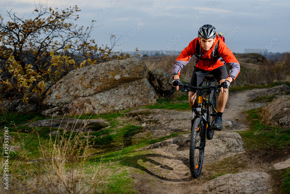 Cyclist in Red Jacket Riding the Bike on the Rocky Trail. Extreme Sport. Space for Text.