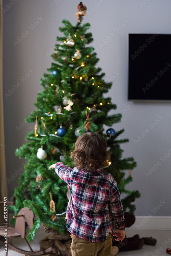 Little boy dresses up a Christmas tree at home