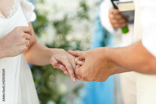 Close-up of groom's hands putting wedding ring on delicate bride © IVASHstudio