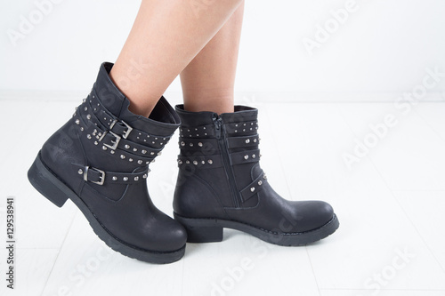 Side View Of Woman's Black Leather Ankle Boots With Straps, Metal Studs And Zipper, Studio Shot Over White Background 