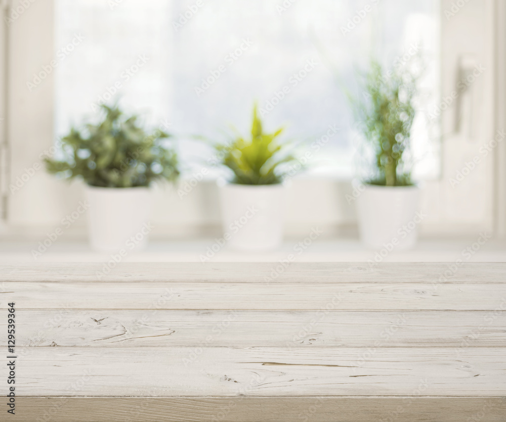 Wooden table on blurred winter window with plant pots background Wooden table on blurred winter window with plant pots background