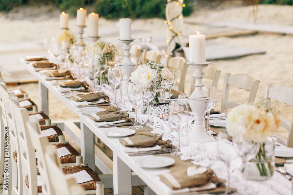 Long dinner table decorated with flaxen cloth and white candles