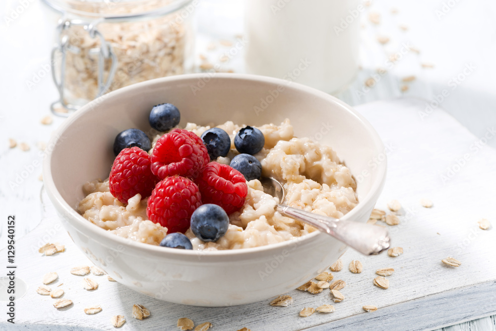 homemade oatmeal with berries on white wooden board, closeup homemade oatmeal with berries on white wooden board, closeup