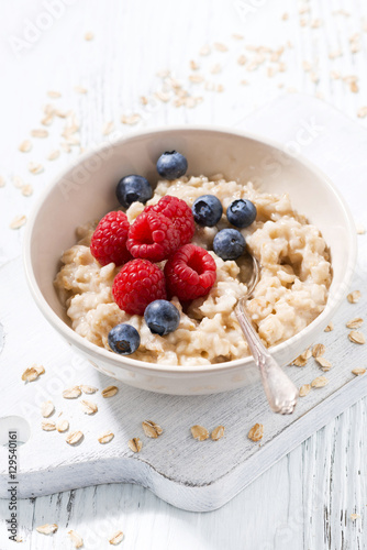 homemade oatmeal with berries on white wooden table, closeup
