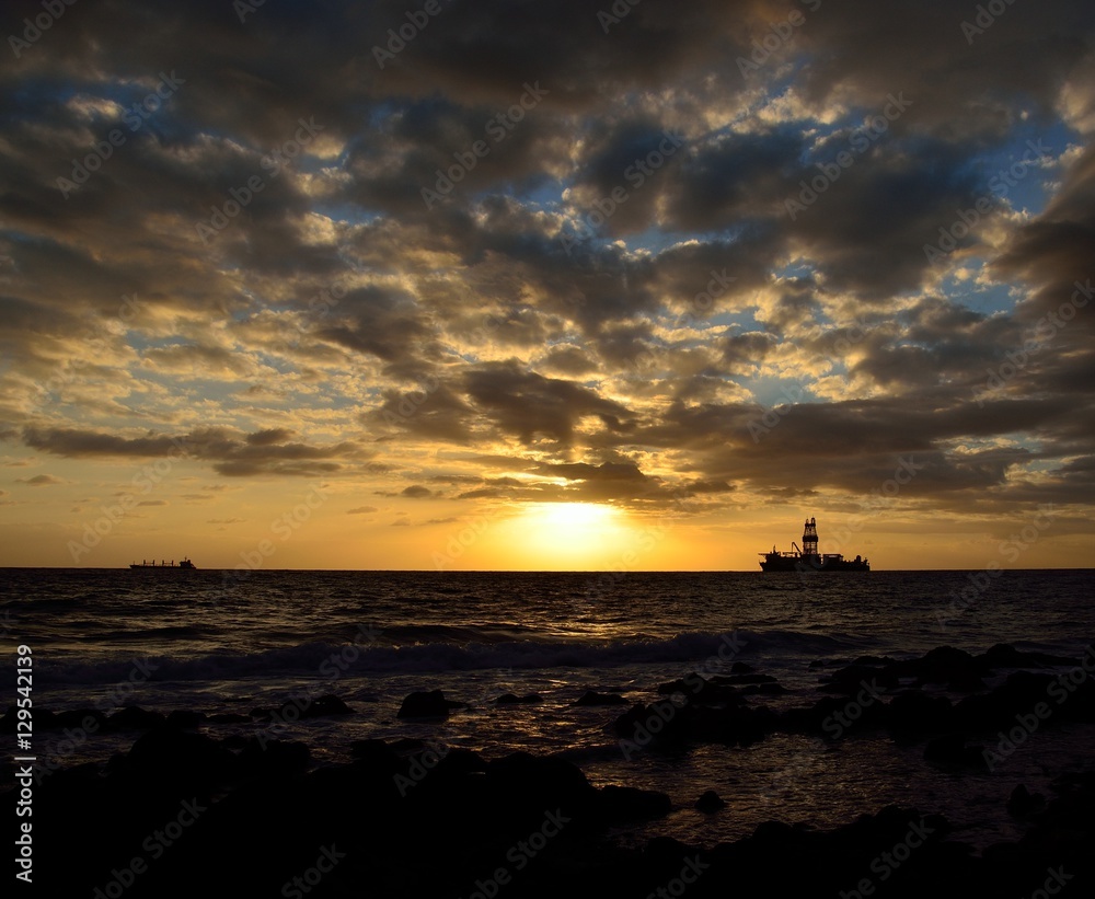 Amazing sunrise from the seashore with low clouds and oil rig in background