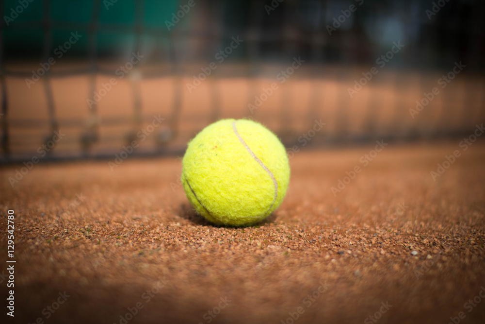 Tennisball liegt vor Tennisnetz auf Sandplatz
