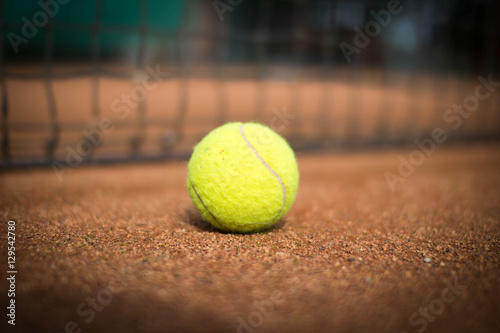 Tennisball liegt vor Tennisnetz auf Sandplatz