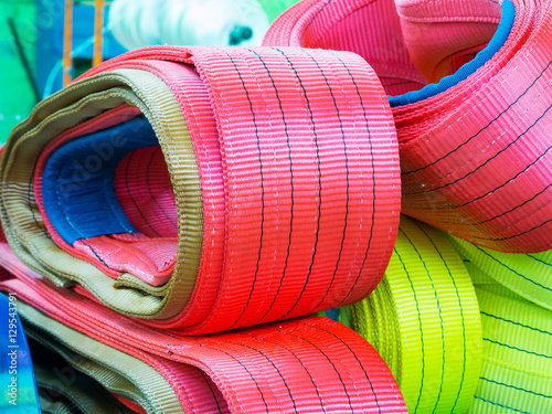 Colorful nylon soft lifting slings stacked in piles photo