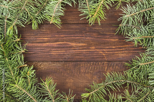 Fir-tree branches on a dark wooden background. Top view, copy sp