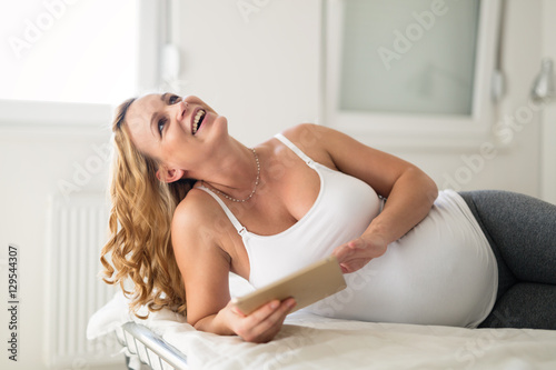 Pregnant woman relaxing and using tablet