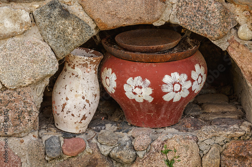 In a stone oven kitchen utensils. Crock, pot and pans. The pot painted with flowers. All covered with dust, rust and cobwebs. For design.