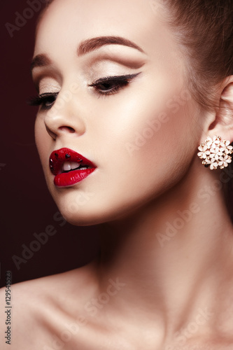 Beauty fashion portrait of a beautiful girl with bright makeup and red lipstick with rhinestones on her lips  close-up.