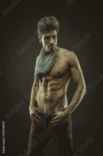 Elegant and muscular man with naked torso and chains around neck