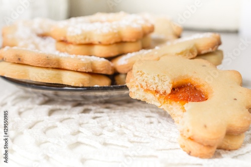 Homemade apricot jam Linzer bite with icing sugar on the white table close up