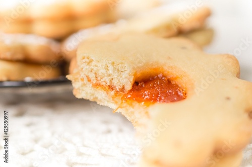 Homemade apricot jam Linzer bite with icing sugar on the white table close up
