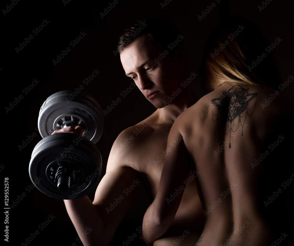 beautiful young sporty sexy couple showing muscle on a dark background beautiful young sporty sexy couple showing muscle on a dark background