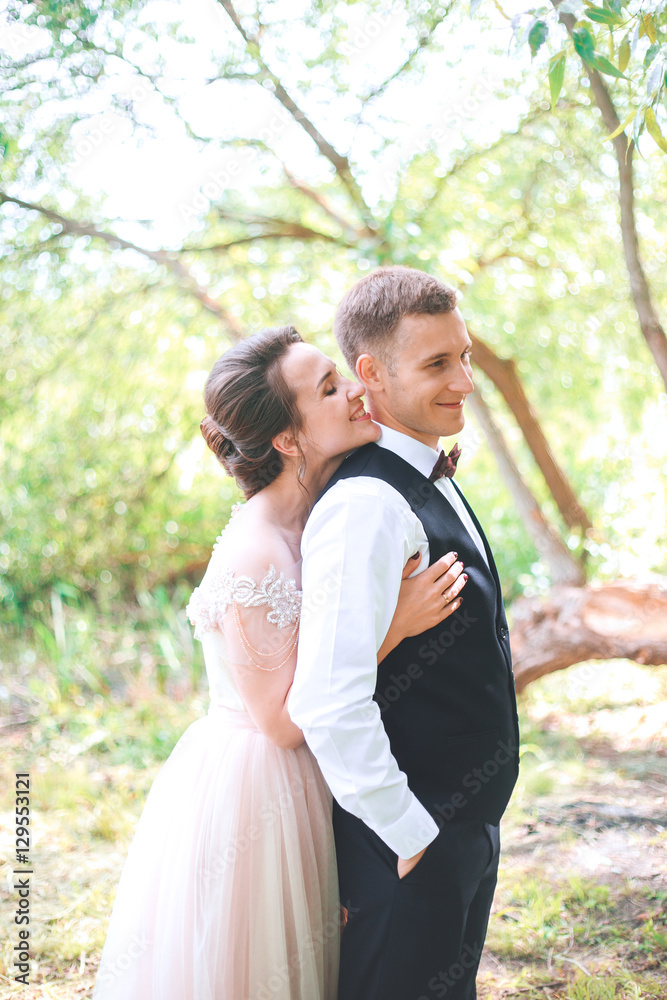 Groom and bride together. couple hugging. Wedding day. Beautiful bride and elegant groom walking after wedding ceremony. Luxury bridal dress and bouquet of flowers. Bride and groom at wedding day Groom and bride together. couple hugging. Wedding day. Beautiful bride and elegant groom walking after wedding ceremony. Luxury bridal dress and bouquet of flowers. Bride and groom at wedding day