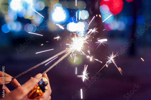 Close up of woman holding sparkler at night. 