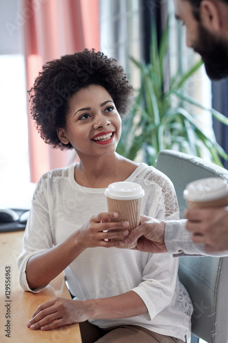 happy woman taking coffee from man in office
