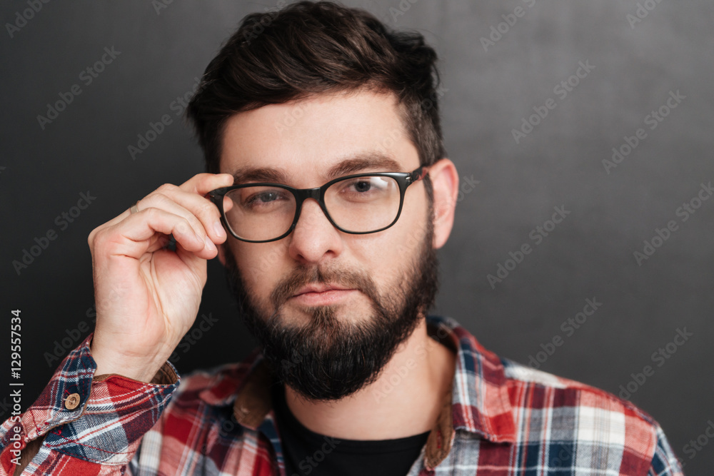 Portrait of serious bearded man touching glasses over chalkboard Portrait of serious bearded man touching glasses over chalkboard