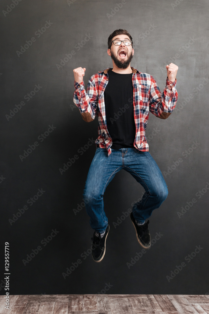 Excited man jumping over chalkboard while make winner gesture