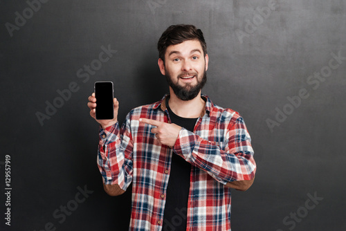 Happy man holding and pointing on blank screen mobile phone