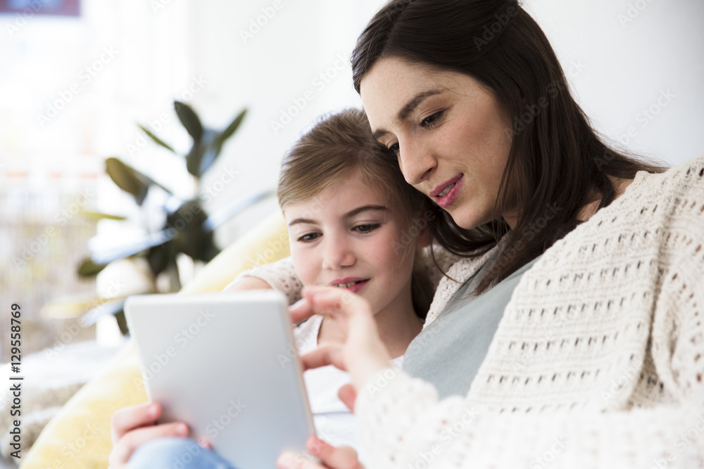 Smiling mother and daughter at home using tablet Smiling mother and daughter at home using tablet