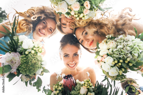 Fotomurale Look from below at happy bride and bridesmaids holding wedding b