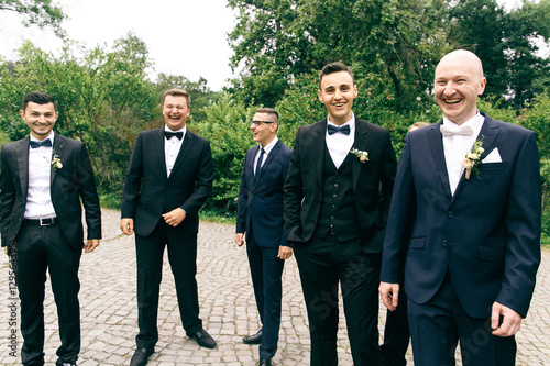 Laughing groom and his friends stand on backyard