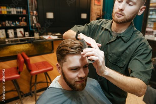 Young hipster man getting haircut by hairdresser