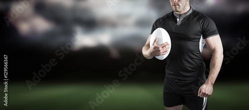 Composite image of tough rugby player holding ball