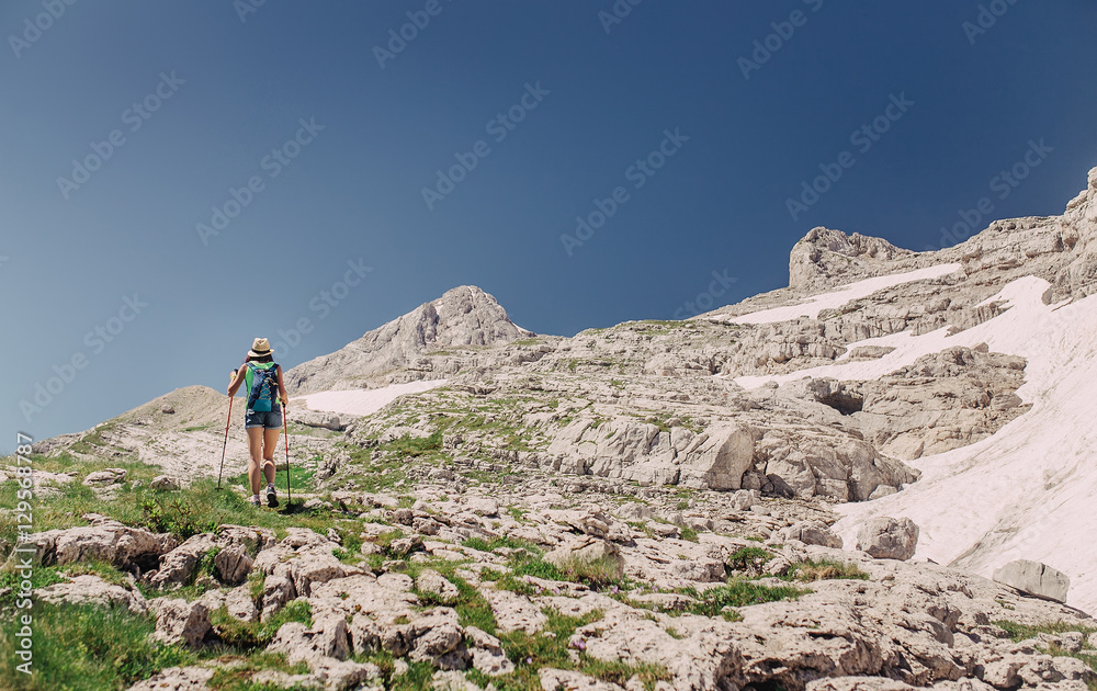 woman passes trekking the rocky highlands of the Dolomite Mountains.