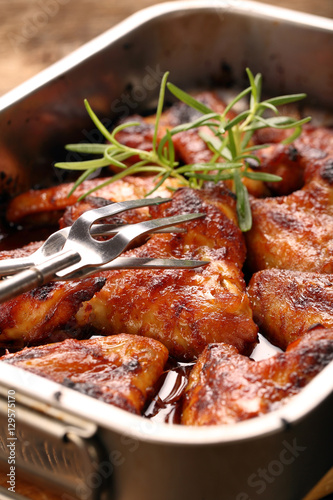 Chicken wings baked in a pan on wooden background