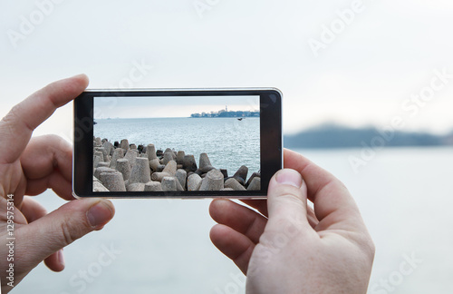 man photographs a mobile phone