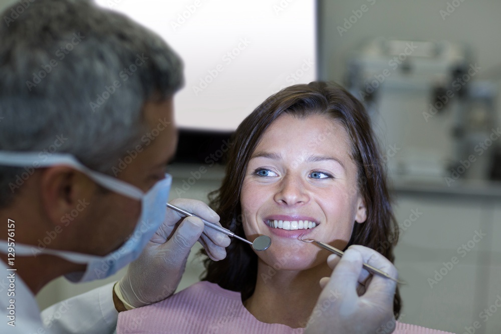 Dentist examining a female patient with tools Dentist examining a female patient with tools