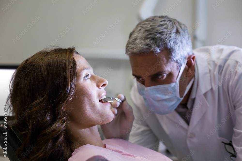 Dentist examining a female patient with tools Dentist examining a female patient with tools