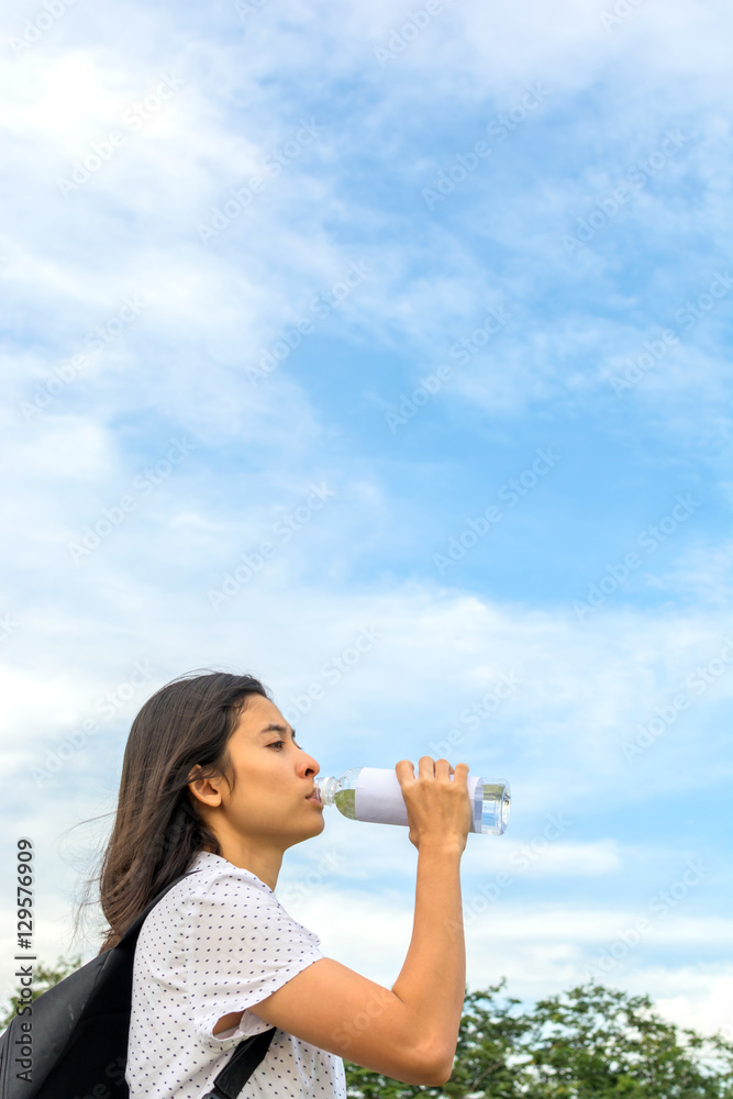 happy young hipster woman with backpack drinking bottled water w happy young hipster woman with backpack drinking bottled water w