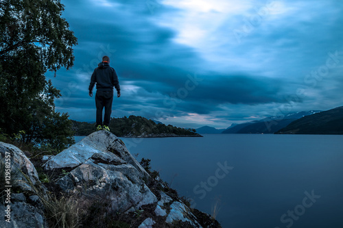 Young man standing on the stone near by fjord at night, Norway © bint87