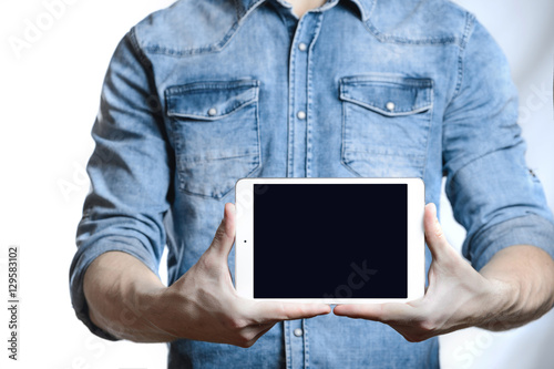 Casual man showing digital tablet computer screen in hands. Isolated on white.